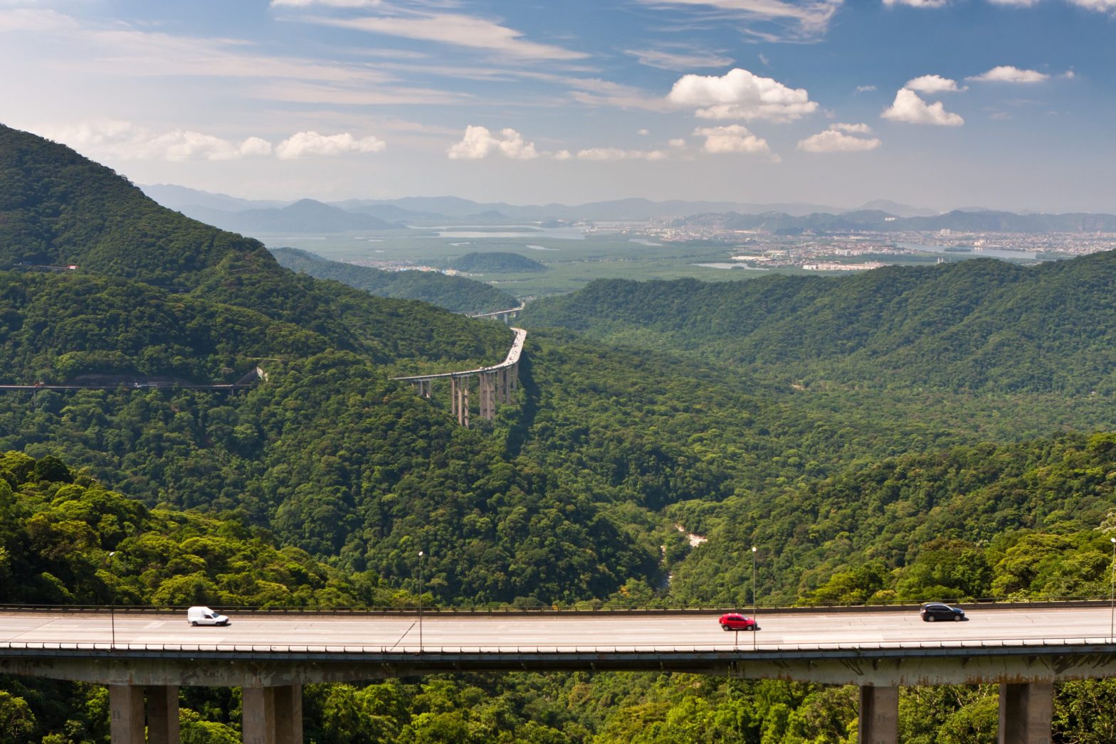 Rodovia Anchieta em trecho de serra com viaduto e veículos em movimento contínuo, cenário do pedágio eletrônico Free Flow com uso da tag ConectCar.
